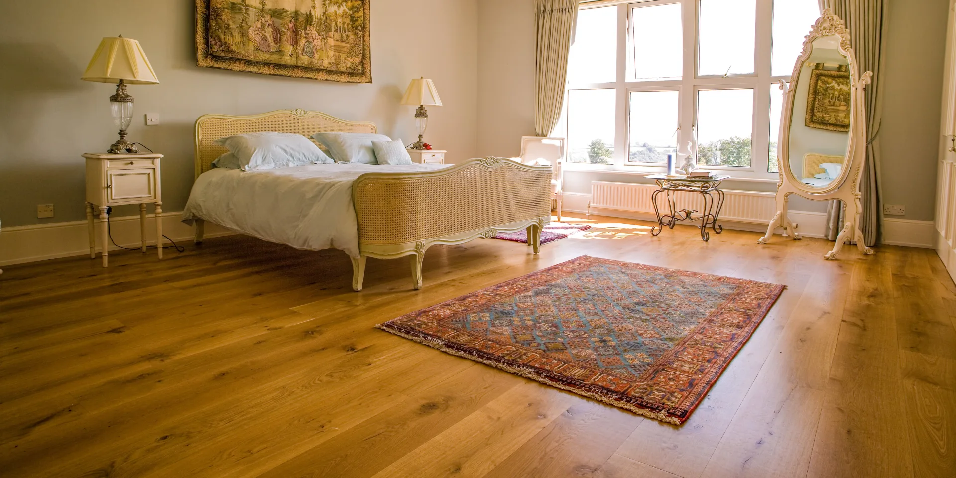 Wide plank oak flooring in a light traditional bedroom